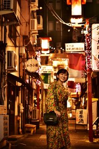 Woman standing on illuminated street at night