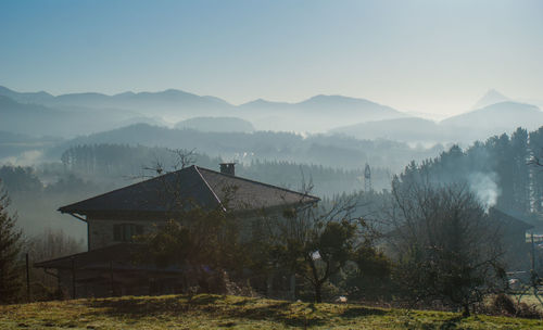 House by trees and buildings against sky