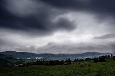 Scenic view of grassy field against cloudy sky