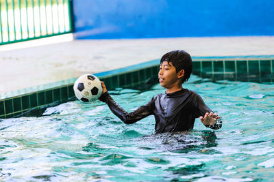 Full length of a boy with ball in swimming pool