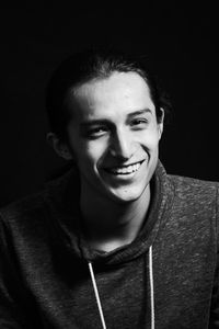 Portrait of smiling young man against black background