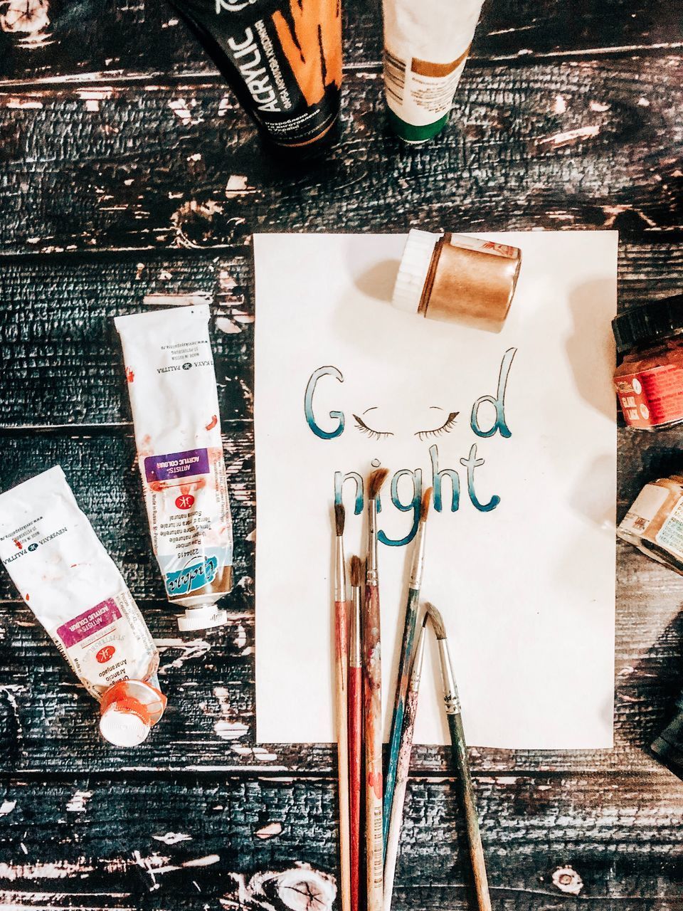 HIGH ANGLE VIEW OF PAINTBRUSHES AND TABLE ON PAPER