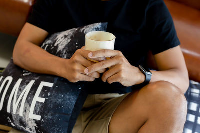 Midsection of man holding coffee cup