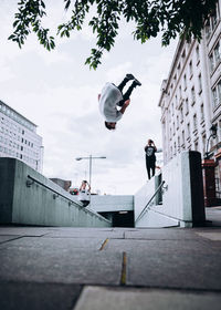 Low angle view of man paragliding against buildings in city