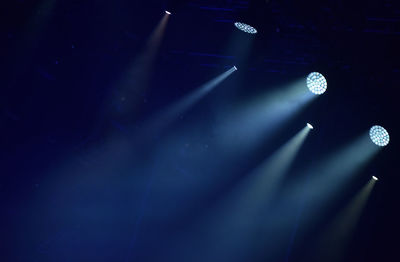 Low angle view of blue spotlights on stage