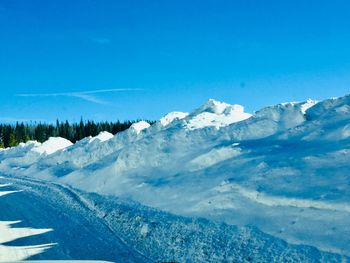 Scenic view of snowcapped mountains against blue sky