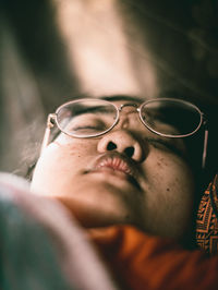 Close-up of woman wearing eyeglasses lying down at home