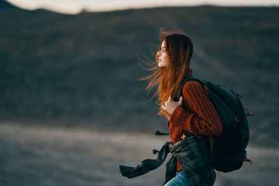 Side view of woman standing against blurred background