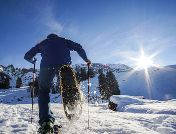 Rear view of man skiing on snowcapped mountain against sky