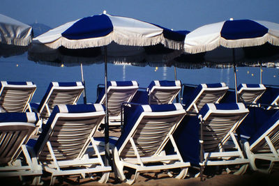 Deck chairs and beach umbrella in row against sky