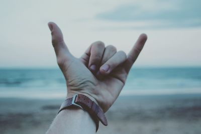 Close-up of hand holding sea against sky