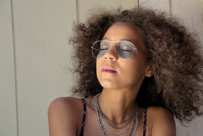 Portrait of beautiful young woman against wall