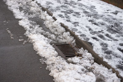 Urban scene of footsteps in a pavement full of snow. drain emerges from the accumulation of snow