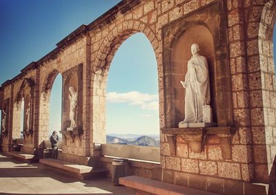 Statues on wall of monastery against sky