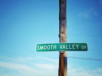 Low angle view of road sign against blue sky