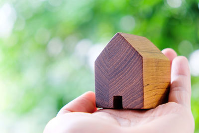 Close-up of hand holding house shaped wood