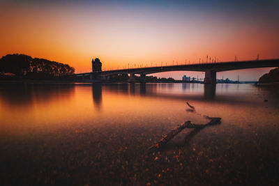 Bridge over river against sky during sunset