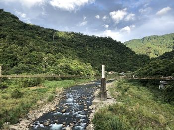 Scenic view of river by mountains against sky