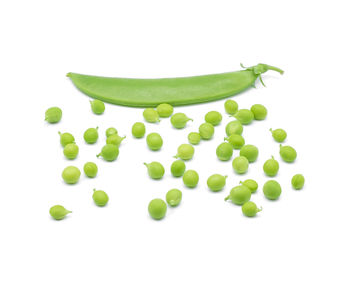 Close-up of peas and pea pod on white background