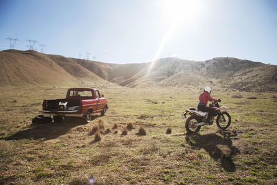 Rear view of female biker riding motorcycle on arid landscape during summer