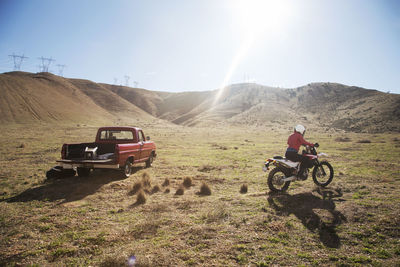 Rear view of female biker riding motorcycle on arid landscape during summer