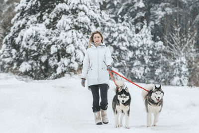 Portrait of woman with dog standing in snow