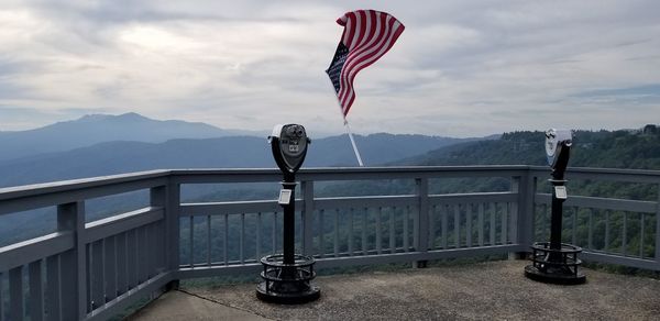 Flag on railing against mountain range against sky