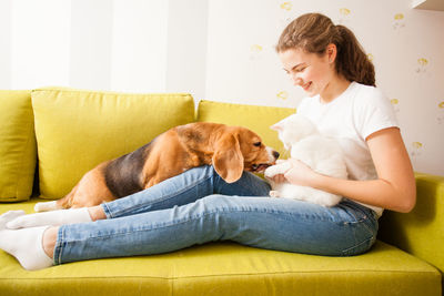 Young woman with pets sitting on sofa at home