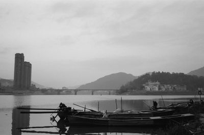 Boat moored on river in city against sky