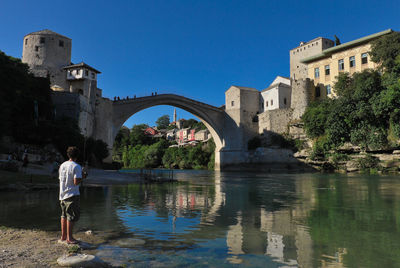 People on bridge over river against sky