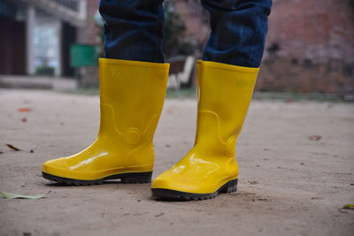 Low section of person wearing yellow rubber boots while standing on land