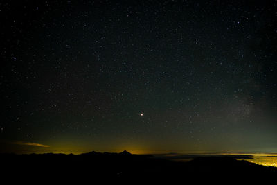 Silhouette landscape against star field at night