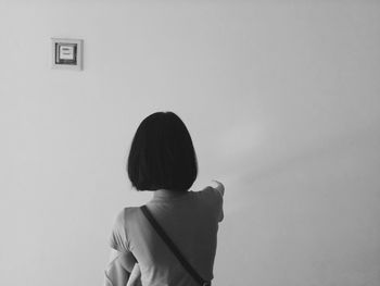 Rear view of woman looking against wall