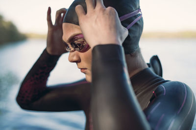 Female swimmer wearing swimming goggles at lakeshore