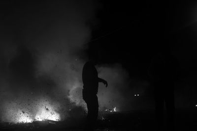 Silhouette of man standing outdoors at night