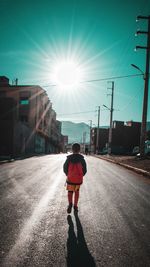 Rear view of man on street against bright sun