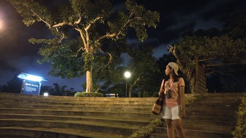 Man standing by illuminated tree against sky at night