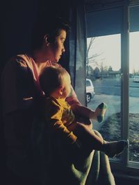 Mother and son looking through window at home