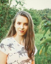 Portrait of beautiful young woman standing against plants