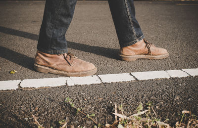 Low section of man wearing shoes on road