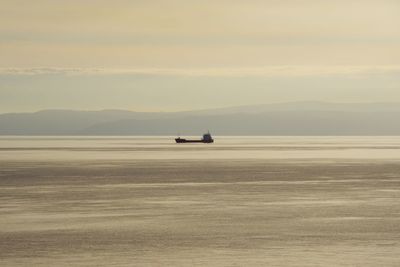 View of boat sailing on water by mountains at dusk