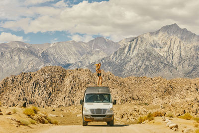 Young woman on roof of camper van on road in northern california.