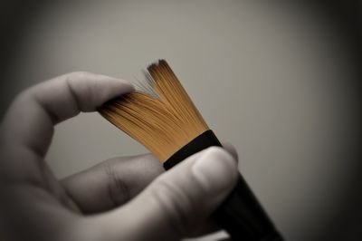 Close-up of cropped hand holding object over white background