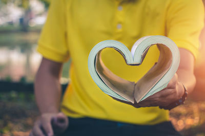 Close-up of woman holding heart shape against blurred background