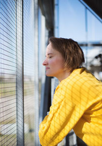 Side view of woman with closed eyes by fence