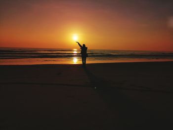 Silhouette woman on beach against sky during sunset