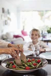 Cropped image of woman serving salad at dining table