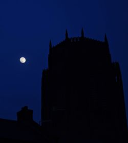 Low angle view of silhouette building against blue sky