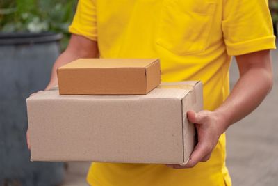 Midsection of man holding yellow while standing in box