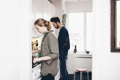 Side view of couple cooking in kitchen at home